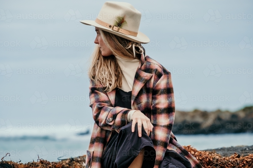 Young woman sitting beside the ocean. - Australian Stock Image