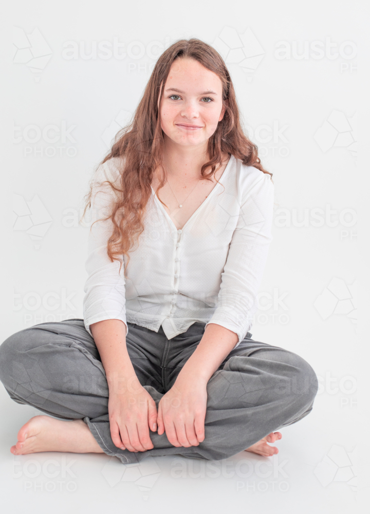 Young woman sitting cross-legged smiling - Australian Stock Image