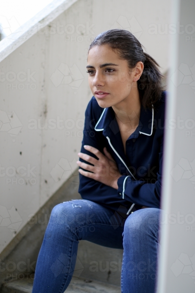 Young woman sitting in stairwell - Australian Stock Image