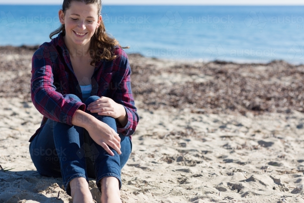 Young woman sitting on beach - Australian Stock Image