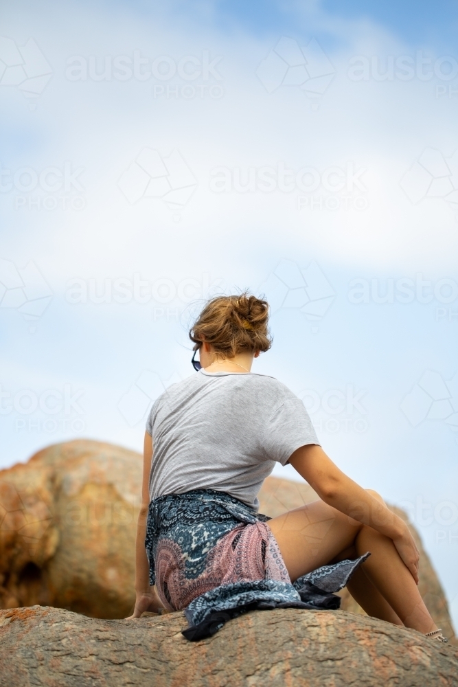 Young woman sitting on rock outdoors - Australian Stock Image