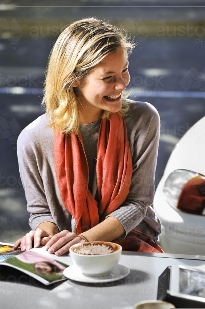 young woman sitting outdoors at a cafe with a coffee - Australian Stock Image