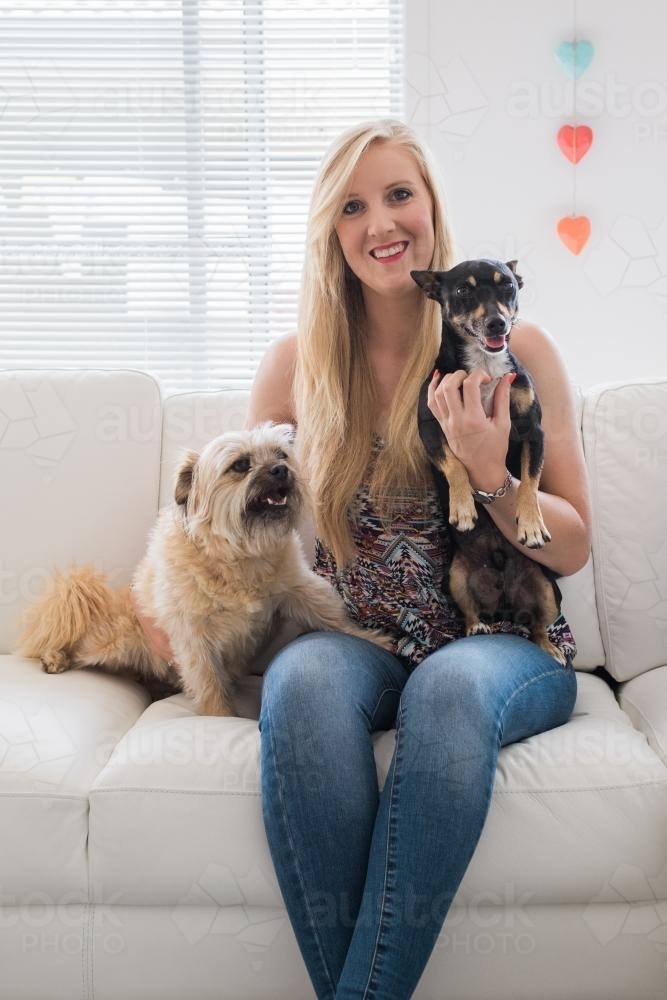 Young woman sitting with two cute puppies - Australian Stock Image