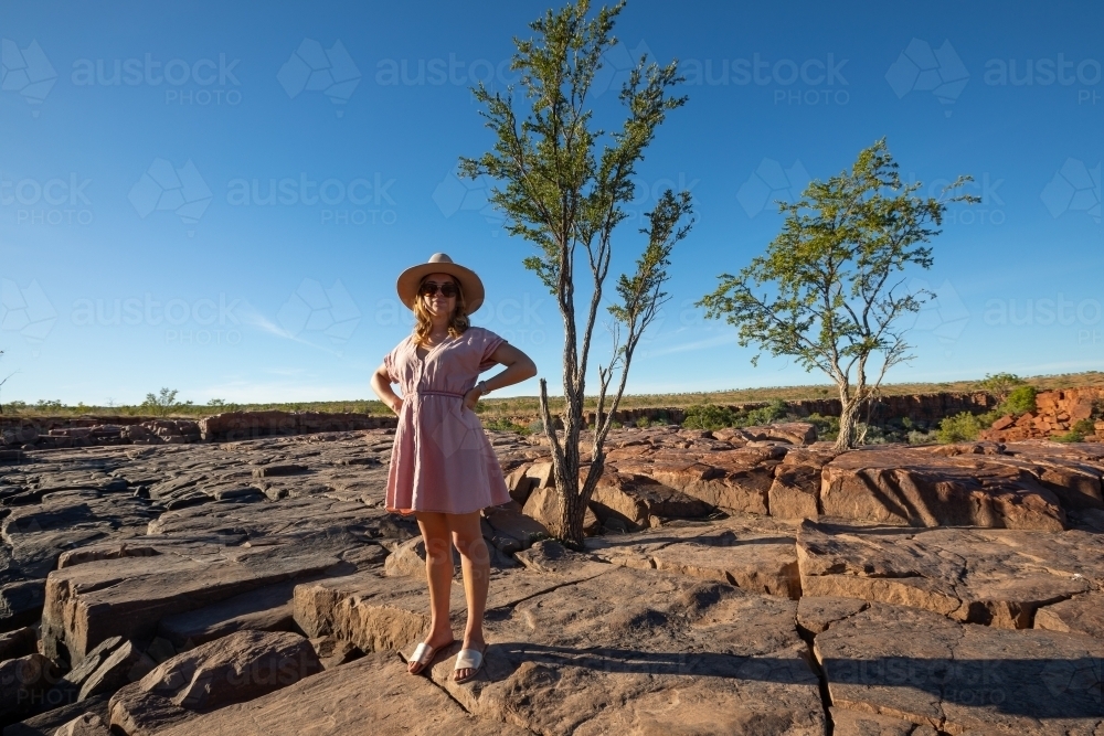 young woman standing in rocky landscape with hands on hips - Australian Stock Image
