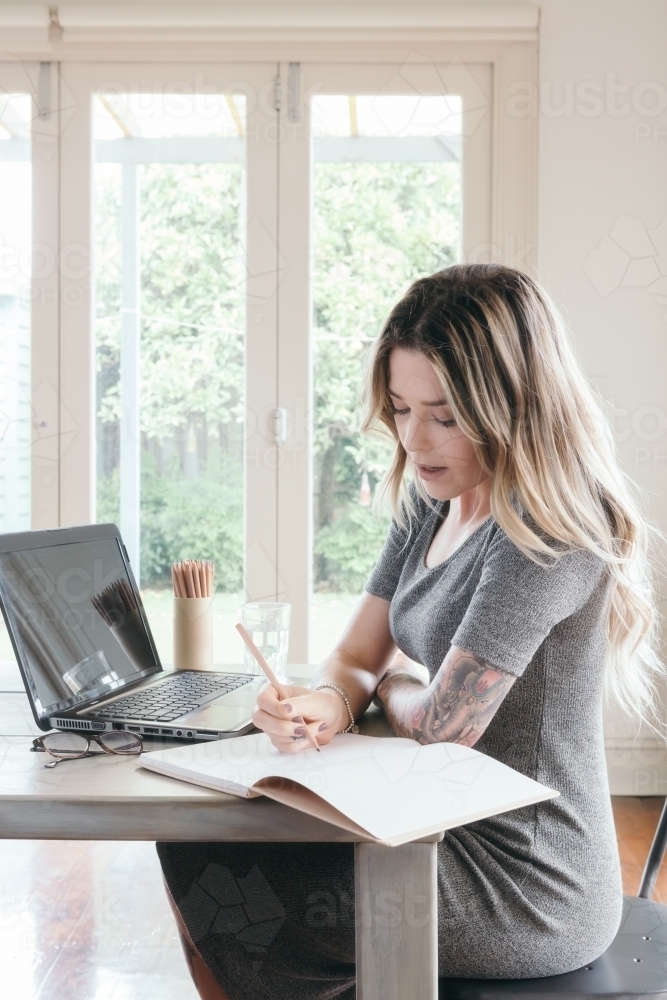 Young woman studying at home with pencil and notepad - Australian Stock Image