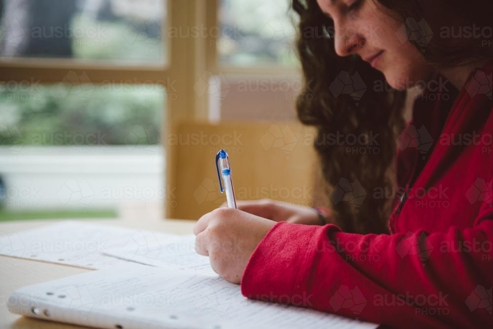 Young woman studying for a test and writing notes at university - Australian Stock Image