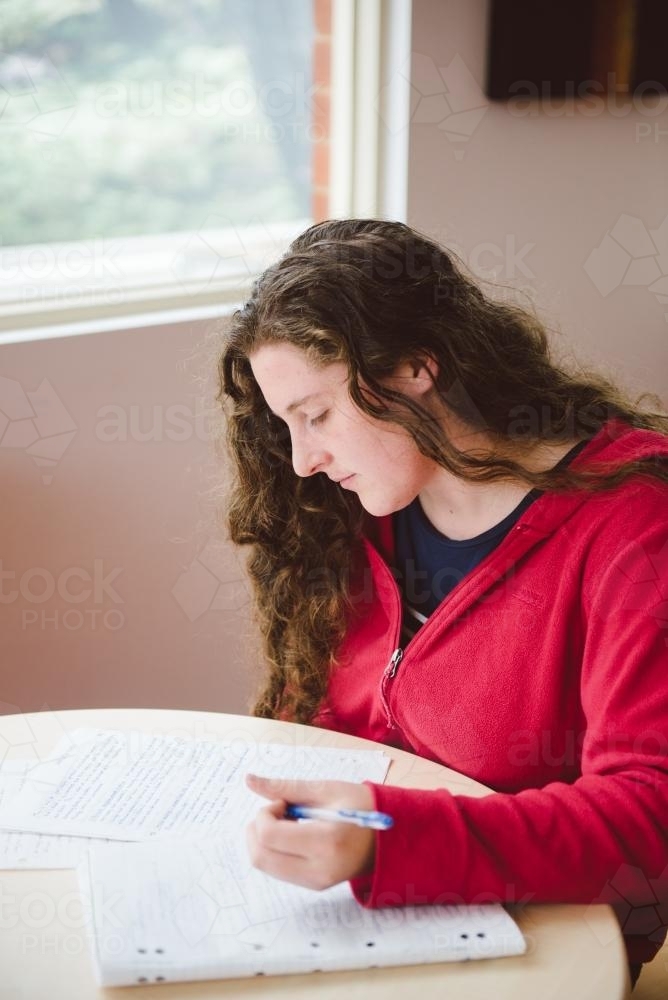 Young woman studying for a test and writing notes at university - Australian Stock Image