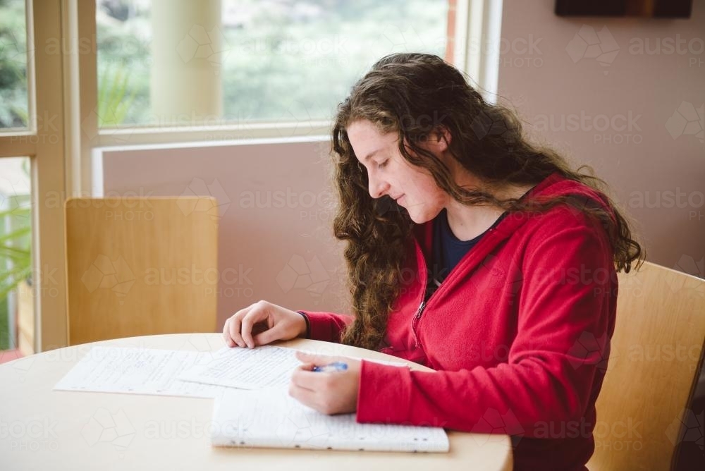 Young woman studying for a test and writing notes at university - Australian Stock Image