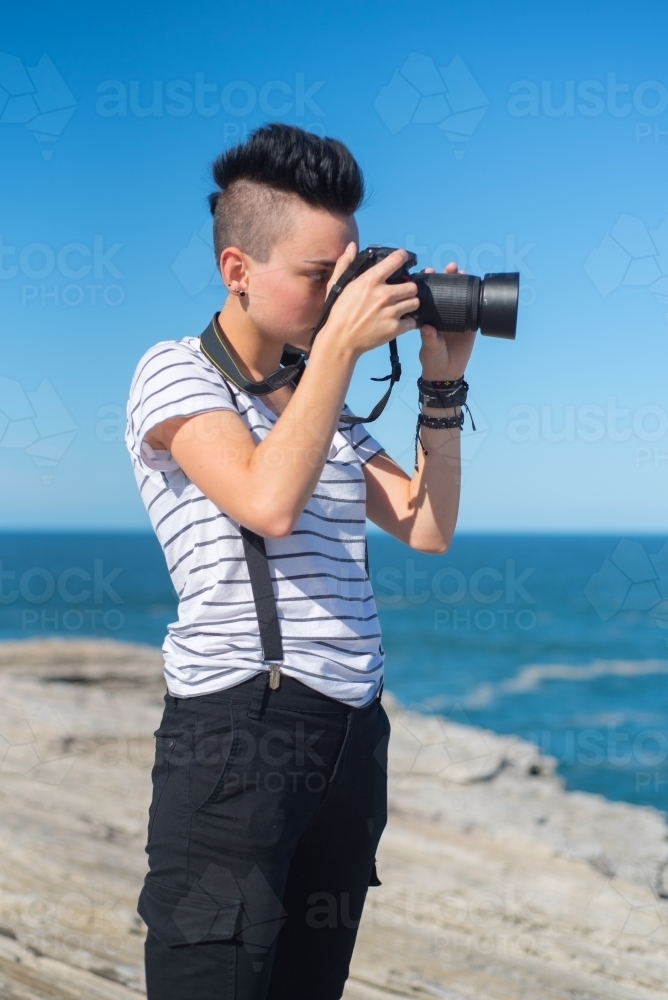 Young woman taking photographs along the coast - Australian Stock Image