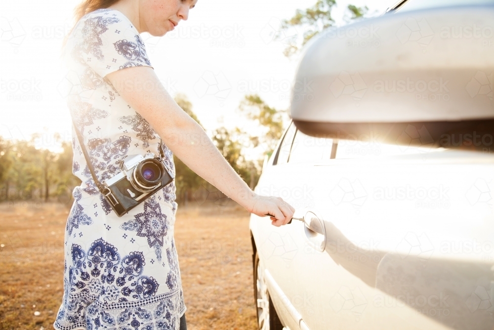 Young woman unlocking car on sunlit afternoon - Australian Stock Image