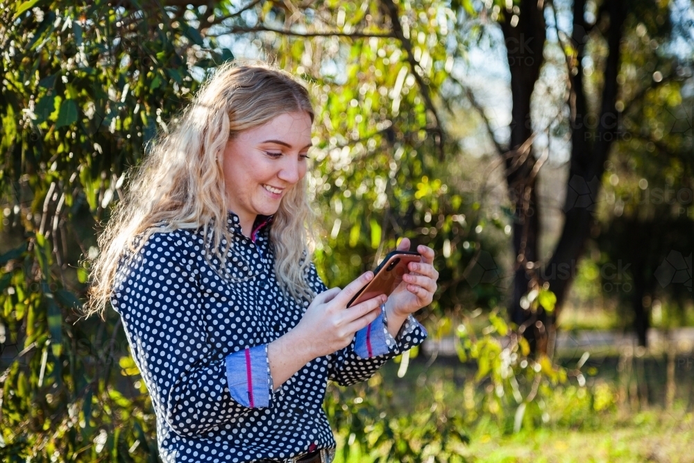 young woman using her mobile phone to keep connected to friends - Australian Stock Image