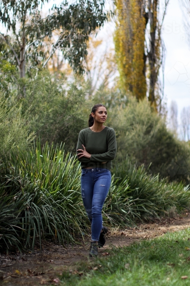 Young woman walking alone in outdoor setting - Australian Stock Image