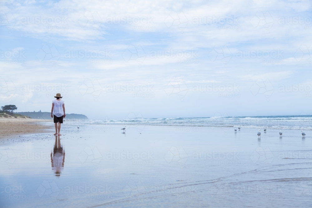 Young woman walking along beachcombing looking for shells at the seaside - Australian Stock Image