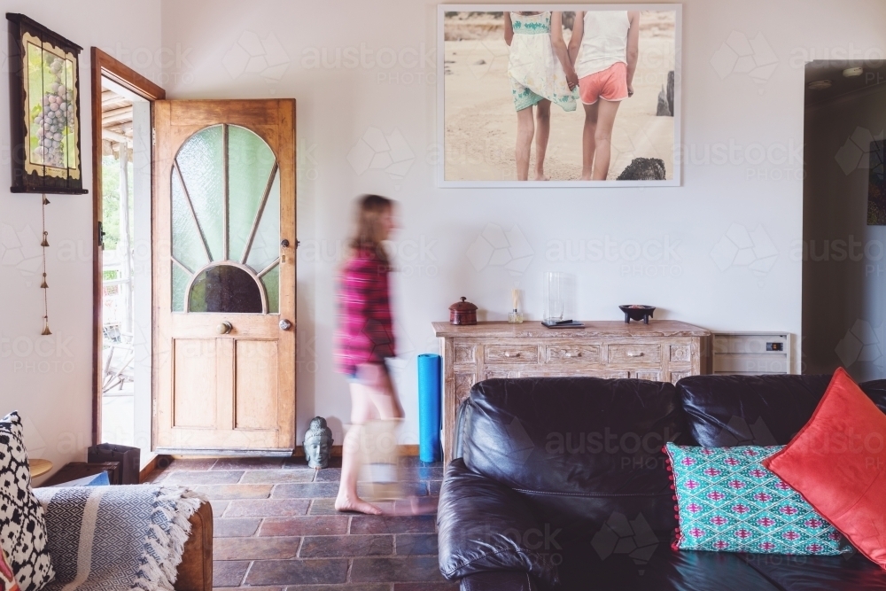 young woman walking in through the front door of a house - Australian Stock Image