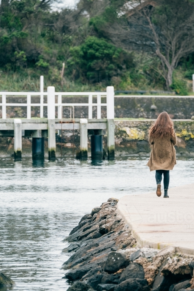 Young woman walking on a jetty by the river. - Australian Stock Image