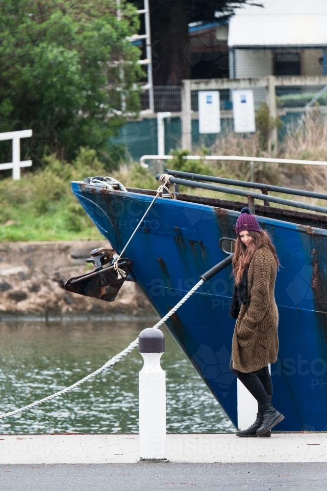 Young woman walking past a boat in the harbour. - Australian Stock Image
