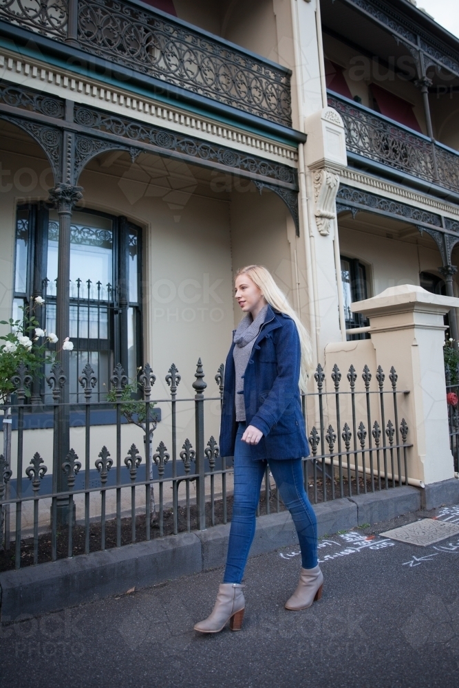 Young Woman Walking Past Terrace Houses - Australian Stock Image