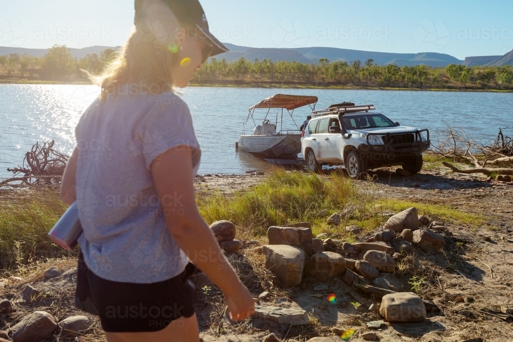 young woman walking towards boat launching on river - Australian Stock Image