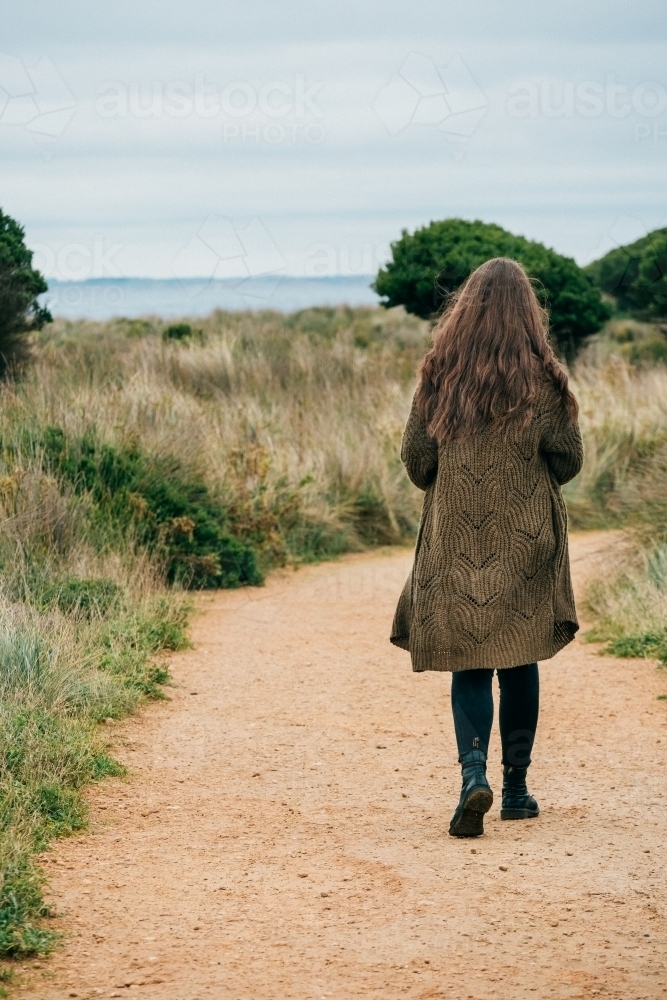 Young woman walks exploring a sandy track. - Australian Stock Image