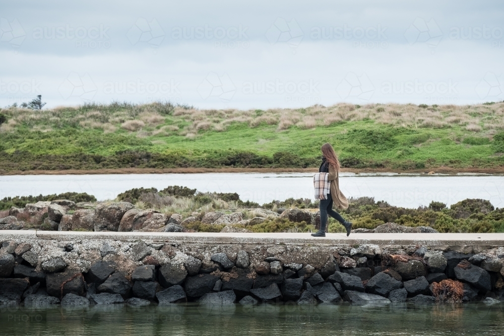 Young woman walks on jetty by the river. - Australian Stock Image