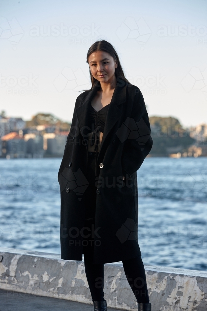 Young woman wearing coat by harbour - Australian Stock Image