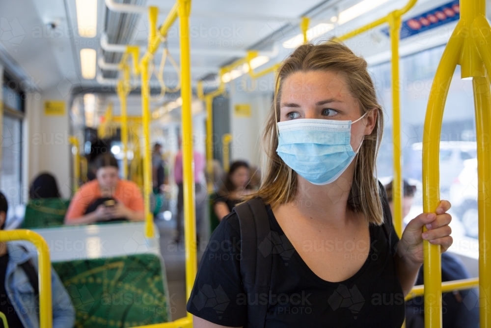 Young Woman Wearing Face Mask Riding the Tram - Australian Stock Image