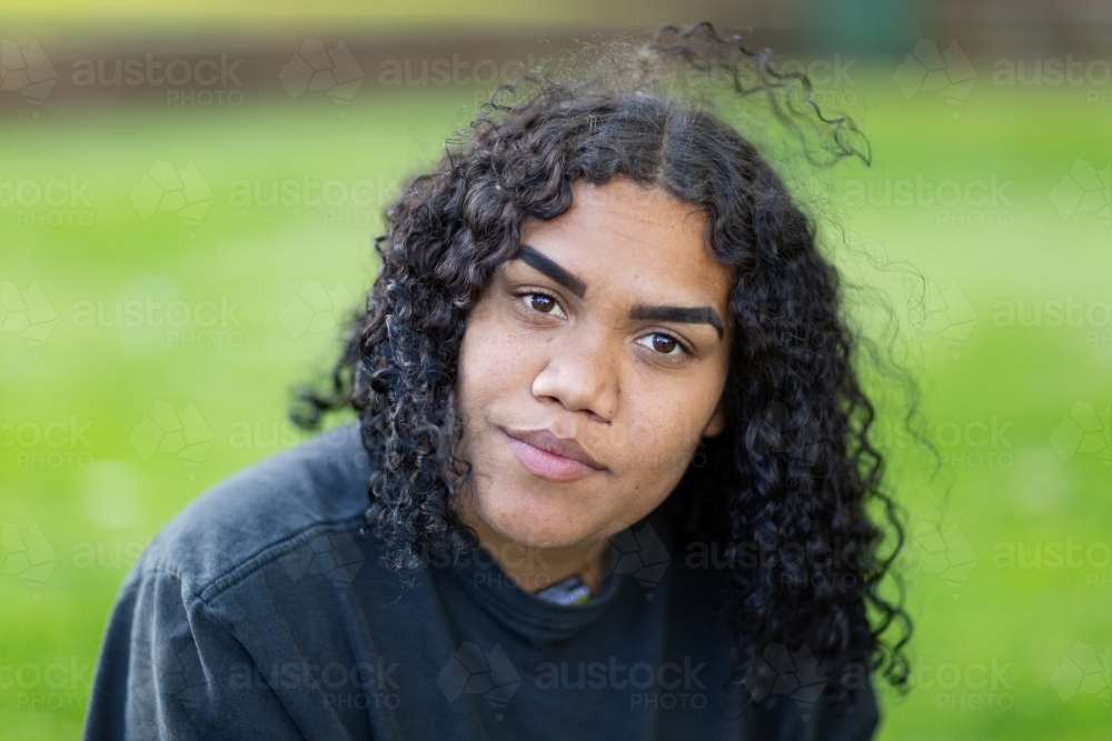 young woman with dark curly hair looking intently - Australian Stock Image