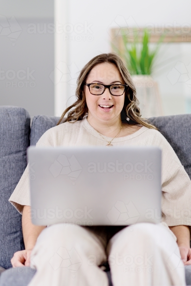 young woman with Down Syndrome using computer at home - Australian Stock Image