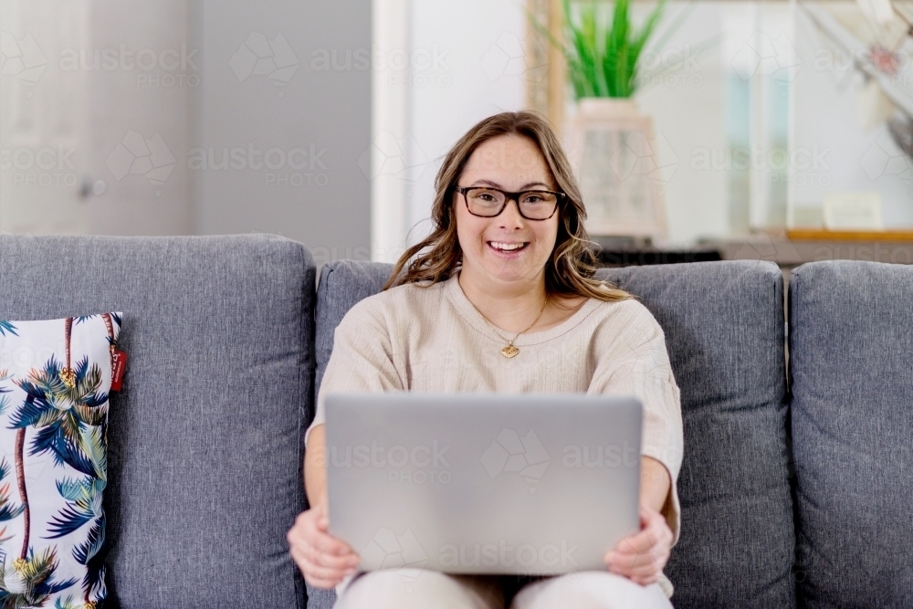 young woman with Down Syndrome using computer at home - Australian Stock Image