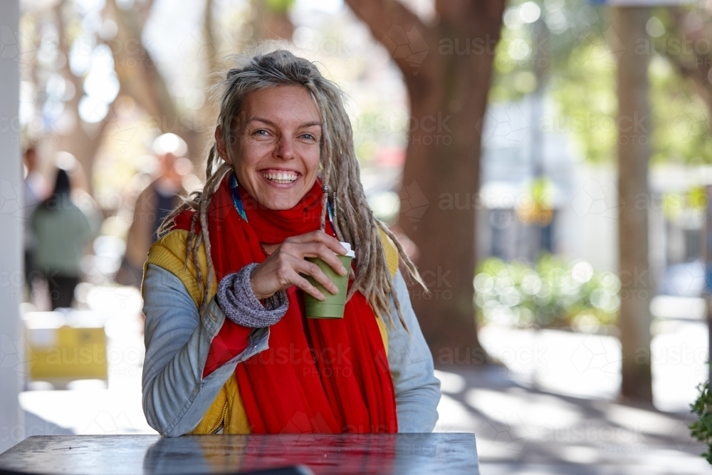 Young woman with dreadlocks smiling over coffee - Australian Stock Image