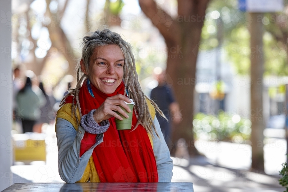 Young woman with dreadlocks smiling over coffee - Australian Stock Image