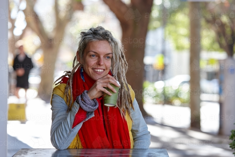 Young woman with dreadlocks smiling over coffee - Australian Stock Image