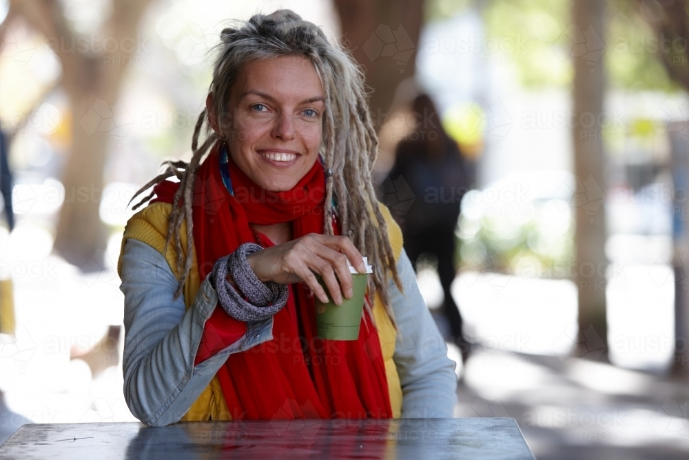Young woman with dreadlocks smiling over coffee - Australian Stock Image