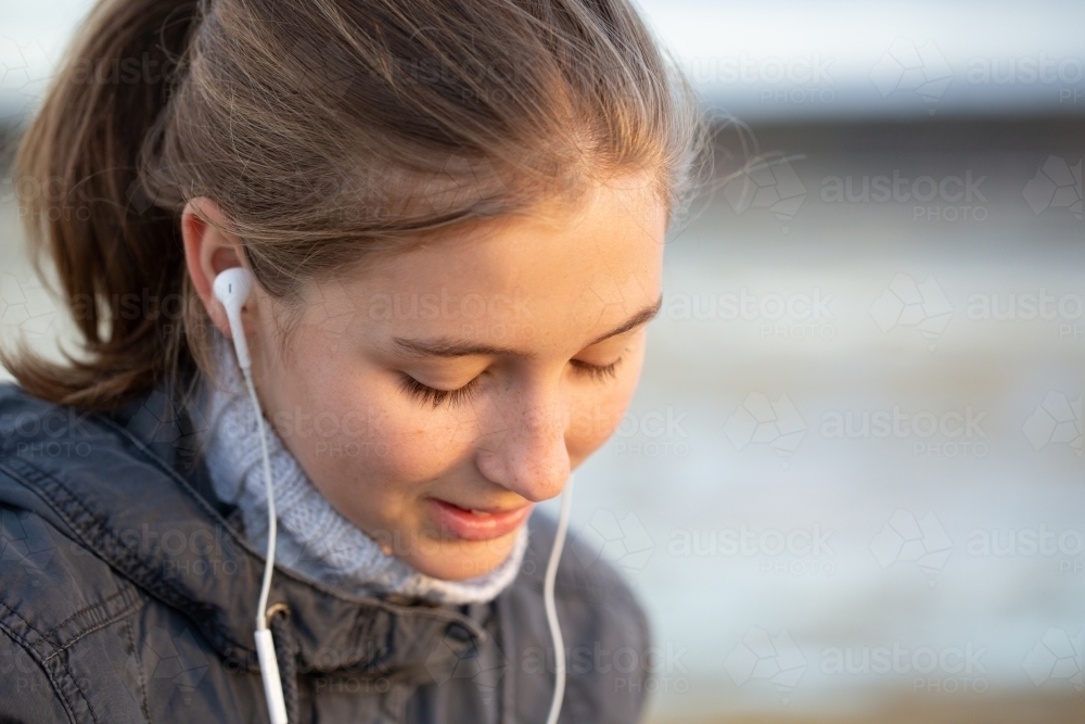 Young woman with earbuds listening to music - Australian Stock Image