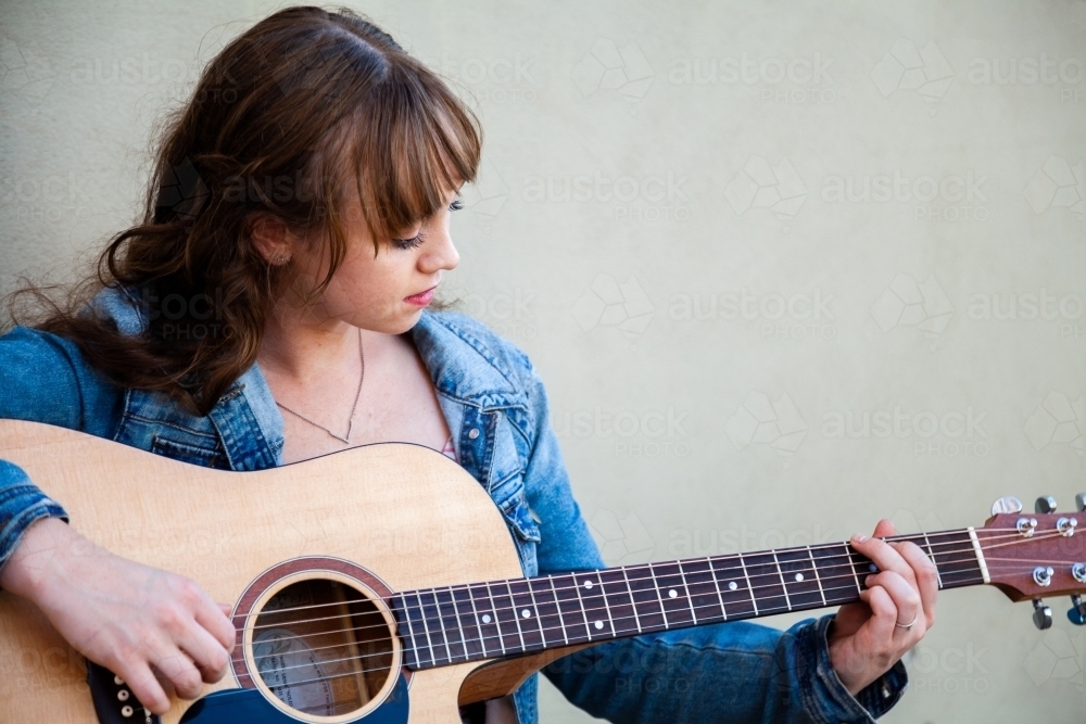 Young woman with guitar and light green copy space - Australian Stock Image