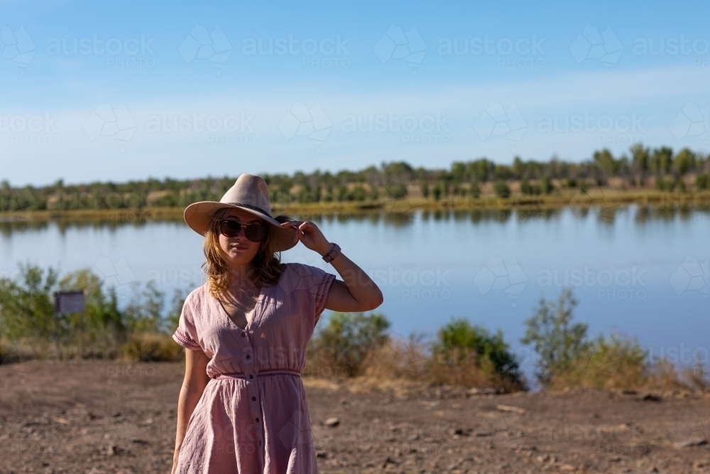 young woman with hand on brim of hat outdoors - Australian Stock Image