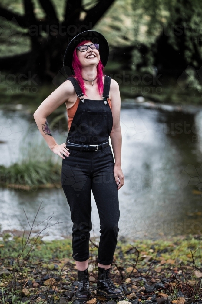 Young woman with pink hair face up into rain laughing - Australian Stock Image