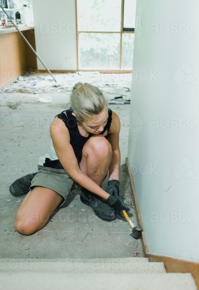 Young Woman Working on Floor at Bottom of Stairs - Australian Stock Image