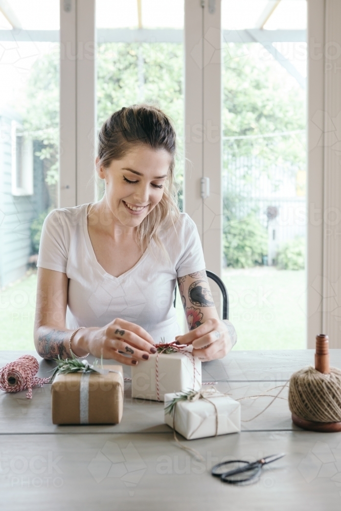 Young woman wrapping gifts in a light bright interior - Australian Stock Image