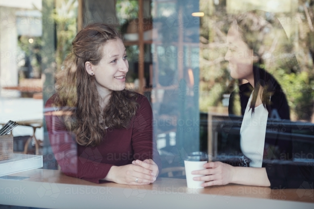 Young women talking at coffee shop - Australian Stock Image