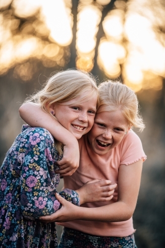 2 girls hugging and smiling with each other - Australian Stock Image
