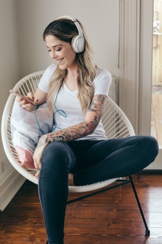 20 something girl listening to a podcast with headphones - Australian Stock Image