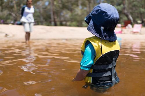 3 year old mixed race boy swims and plays in a river - Australian Stock Image