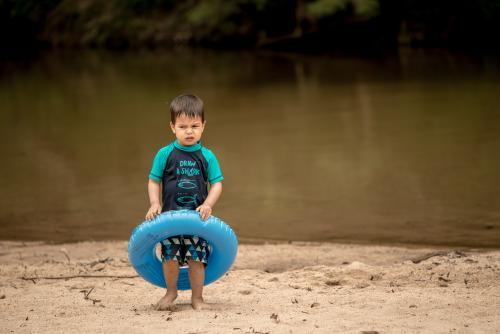 3 year old mixed race boy swims and plays in a river - Australian Stock Image