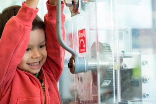 4 year old mixed race boy presses a souvenir penny at a local Sydney tourist attraction - Australian Stock Image