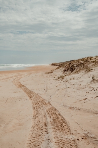 4WD tyre tracks leading down a deserted beach