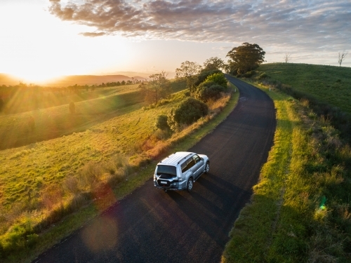 4X4 car driving on country road trip adventure into the sunset