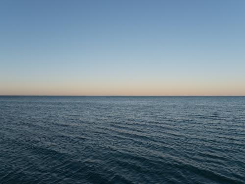 50:50 split calm blue sea and blue sky at dusk - Australian Stock Image