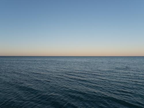50:50 split calm blue sea and blue sky at dusk