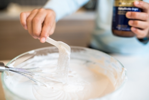 7 year old mixed race boy cooks at home with a whisk and bowl - Australian Stock Image